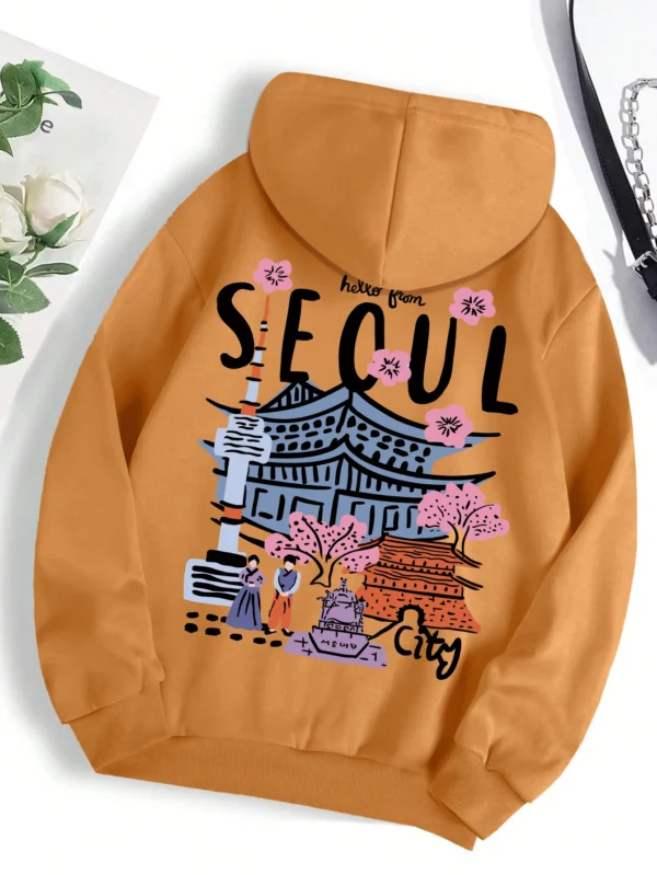 Woman wearing a comfortable warm fleece hoodie with a scenic Seoul print design and artificial fur lining visible inside the hood.