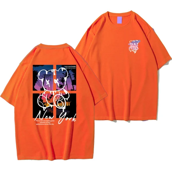 Men's loose fit cotton t-shirt displaying a colorful graphic print of a cartoon bear in front of a New York sunset scene.