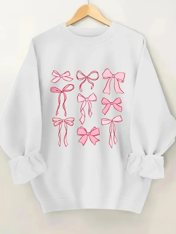 Woman wearing a pink hoodie with an all-over white bow print and fleece lining.