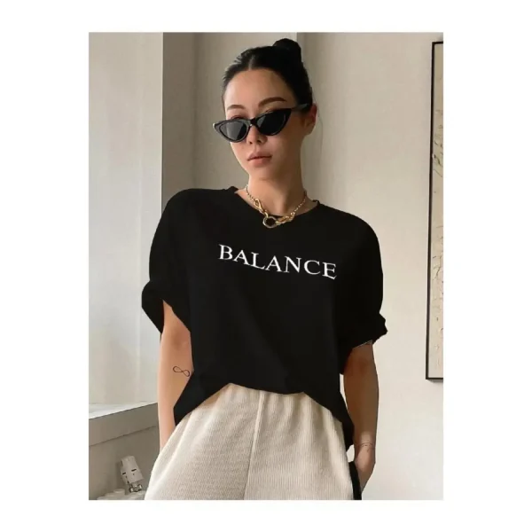 Woman wearing white oversized 'Balance' graphic print cotton t-shirt with loose fit and short sleeves.