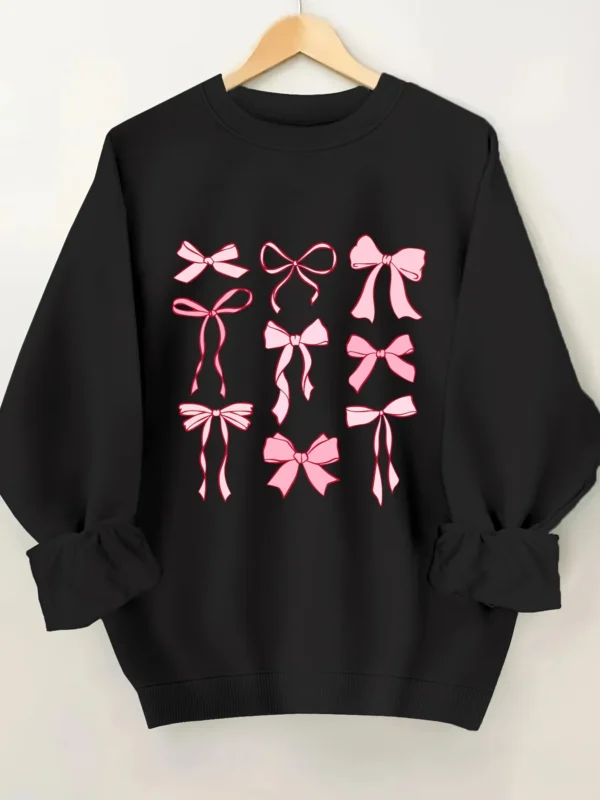 Woman wearing a pink hoodie with an all-over white bow print and fleece lining.