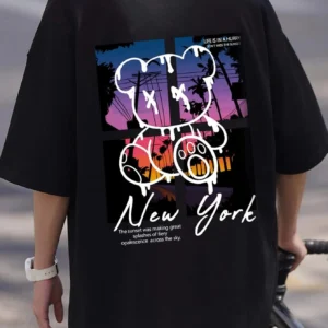 Men's loose fit cotton t-shirt displaying a colorful graphic print of a cartoon bear in front of a New York sunset scene.