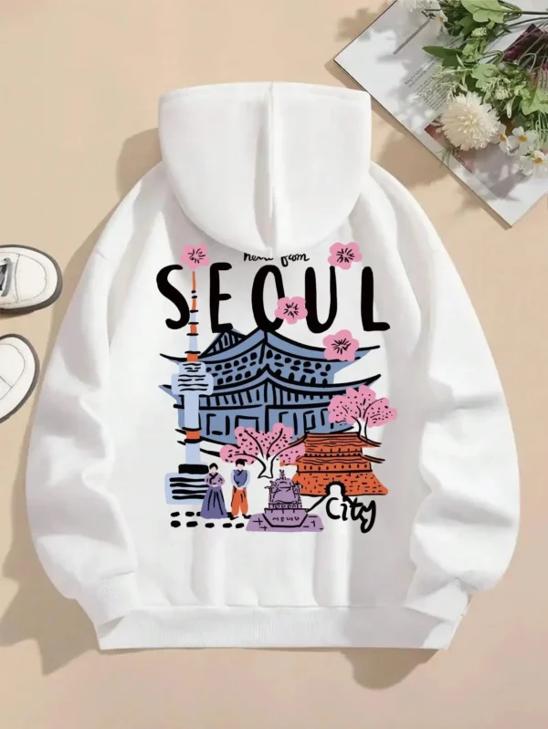 Woman wearing a comfortable warm fleece hoodie with a scenic Seoul print design and artificial fur lining visible inside the hood.