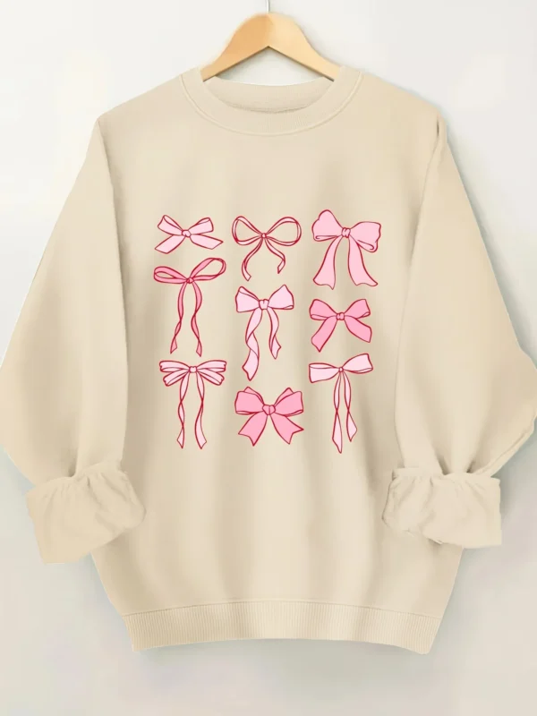 Woman wearing a pink hoodie with an all-over white bow print and fleece lining.