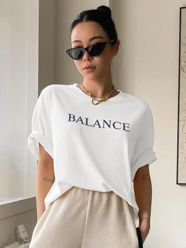 Woman wearing white oversized 'Balance' graphic print cotton t-shirt with loose fit and short sleeves.