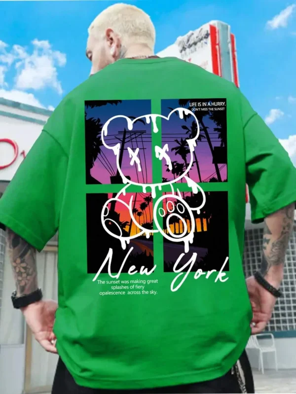 Men's loose fit cotton t-shirt displaying a colorful graphic print of a cartoon bear in front of a New York sunset scene.