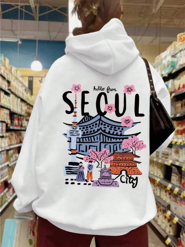 Woman wearing a comfortable warm fleece hoodie with a scenic Seoul print design and artificial fur lining visible inside the hood.