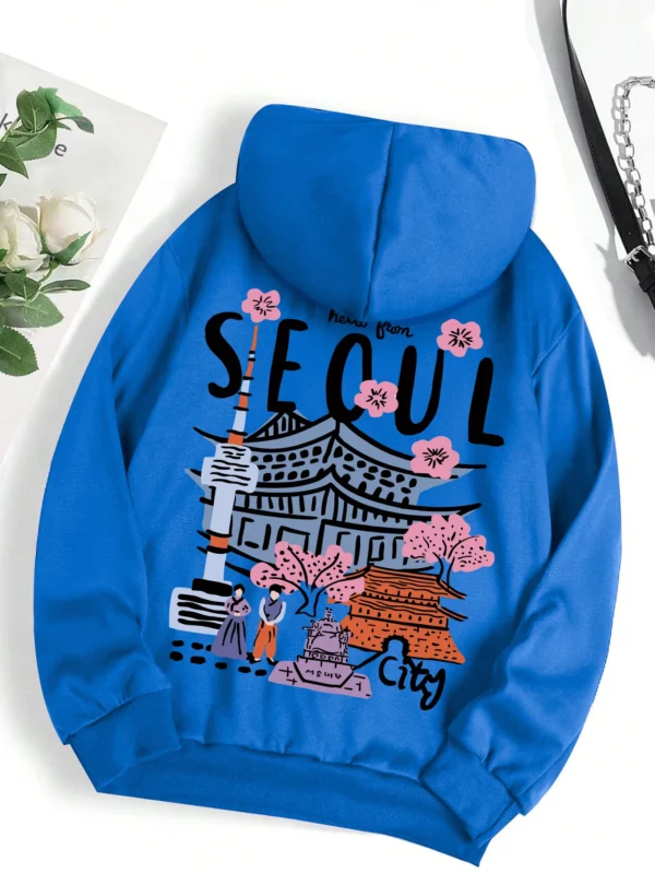 Woman wearing a comfortable warm fleece hoodie with a scenic Seoul print design and artificial fur lining visible inside the hood.