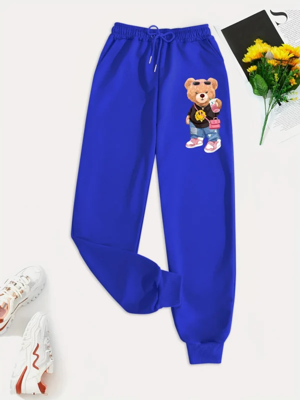 Woman models loose-fit sweatpants featuring cartoon bear print on the leg