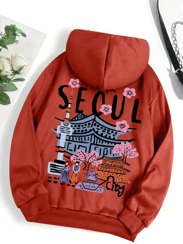 Woman wearing a comfortable warm fleece hoodie with a scenic Seoul print design and artificial fur lining visible inside the hood.