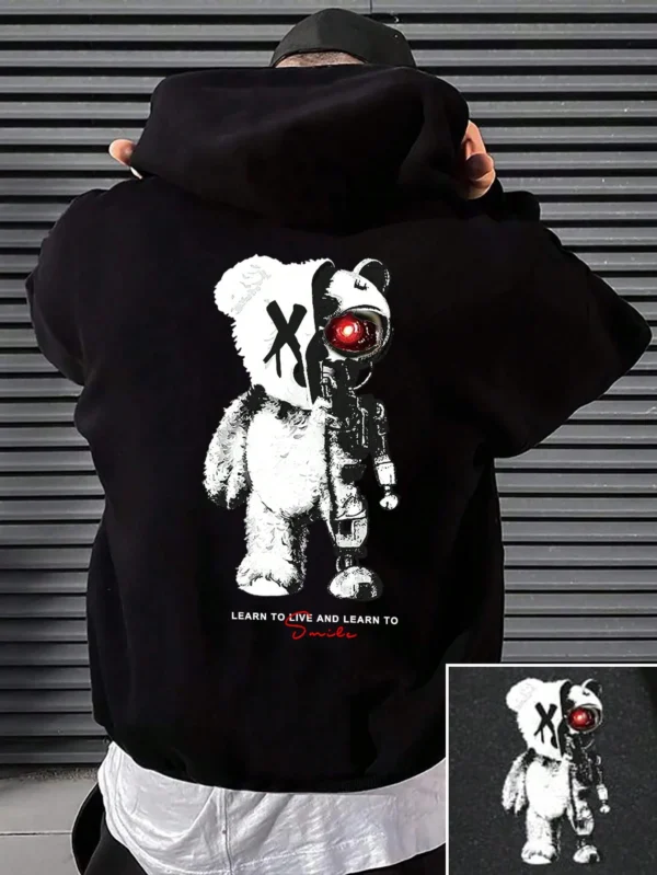 Man wearing a casual oversized black hoodie featuring a large white cartoon bear graphic print on the front.