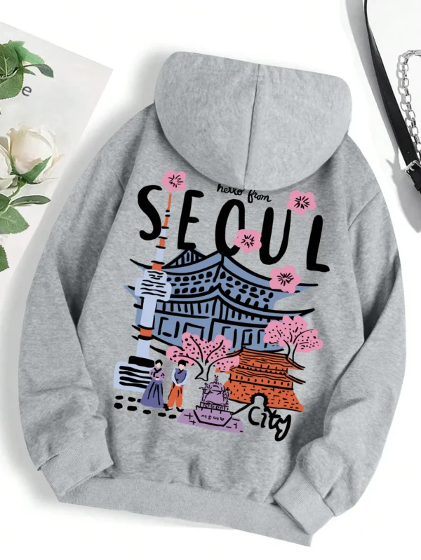 Woman wearing a comfortable warm fleece hoodie with a scenic Seoul print design and artificial fur lining visible inside the hood.
