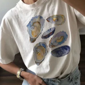 Woman wearing a casual white t-shirt with a blue and beige vintage seashell print.