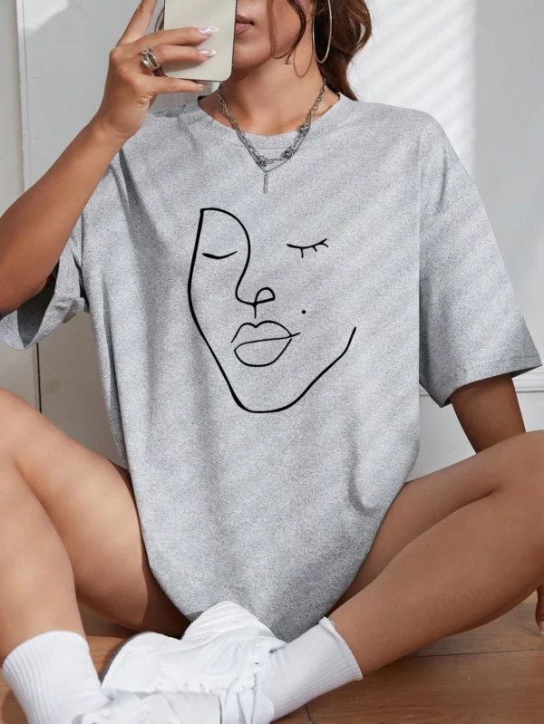 Woman wearing white cotton t-shirt with black minimalist line art face print. Casual short sleeve regular fit style. ```