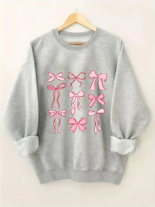 Woman wearing a pink hoodie with an all-over white bow print and fleece lining.